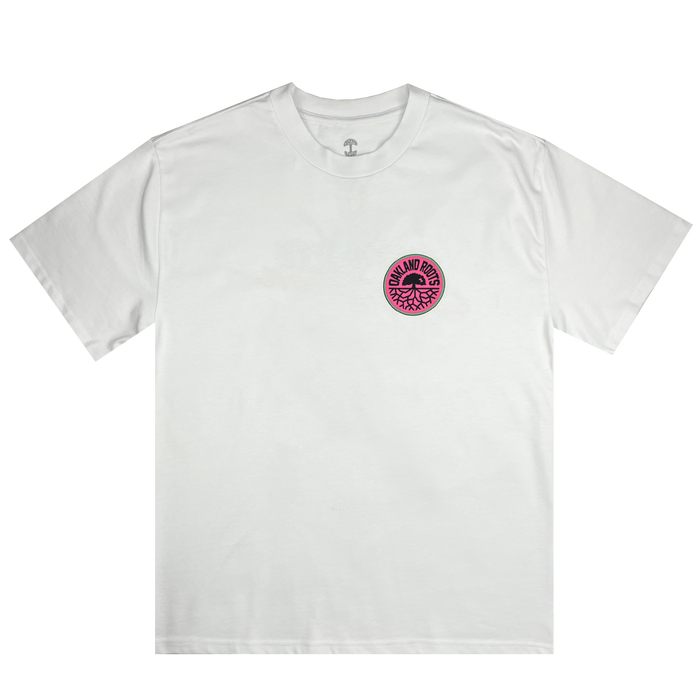 A Staycation Heavy Tee from Oakland Roots SC with a boxy fit features a plain white design. It has a round logo on the left chest, showcasing "ROCK AND ROLL" text encircling an intricate central graphic. The logo stands out with its pink background and dark red and black text and graphics.