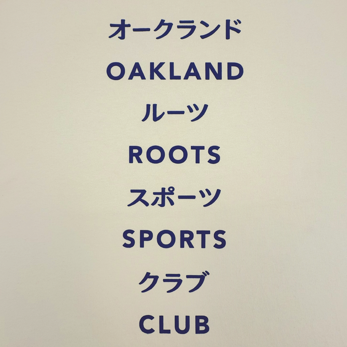 Text on a plain background reads: オークランド (Oakland), ルーツ (Roots), スポーツ (Sports), クラブ (Club), with each English word below its Japanese equivalent—perfect for fans of the Oakland Roots SC Story Telling Tee.