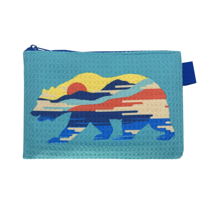 The Sunset Bear Pouch by Oaklandish is a small blue zip pouch with a top zipper, featuring a stylized California grizzly design. The bear is depicted in a colorful pattern showcasing elements of nature such as mountains, a sunset, and a forest, primarily using red, yellow, blue, and beige hues.