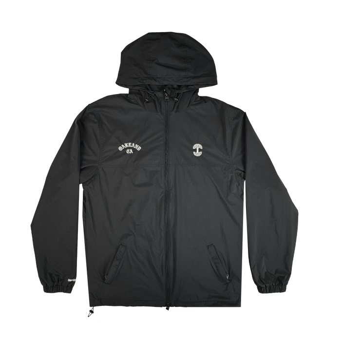 The Oaklandish Susurrus Track Top is a sleek black nylon hooded jacket with a front zipper, elastic cuffs, and two front pockets. "OAKLAND CA" is printed in white on the left chest; a small white circular logo accents the right chest.