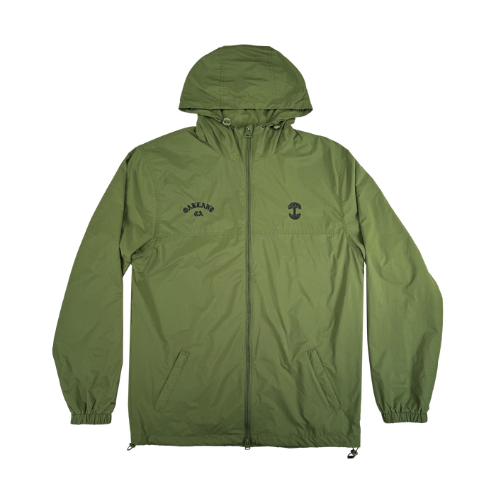 The Oaklandish Susurrus Track Top is a lightweight olive green nylon jacket with a classic fit, hood, front zipper, elastic cuffs, and two side pockets. Features include a small black left-chest graphic and "CAKELAND" logo on the right.