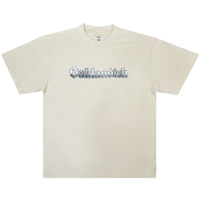 A cream-colored classic fit t-shirt, the Oaklandish Swoop Tee features the brand’s name in bold black Old English-style lettering across the chest. Made from heavyweight cotton, this men’s tee—shown laid flat on a white background—boasts short sleeves and a crew neckline.