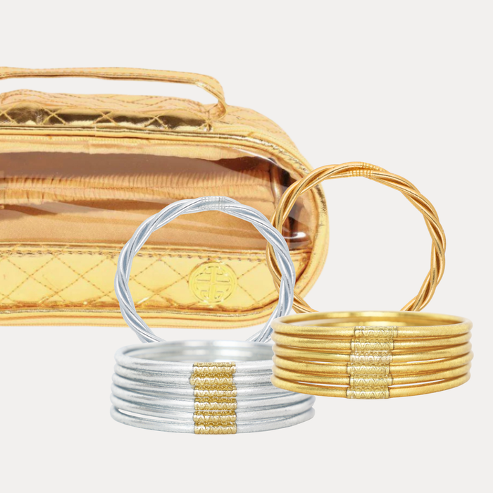 Two stacked bangle bracelets in front of a gold quilted pouch: one set is silver, and the other is gold. The bracelets are photographed on a clean light gray background.