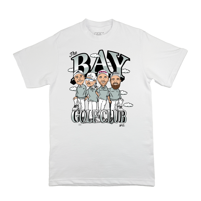 The Bay Golf Club Tee by By DOC features a whimsical Canalin-style illustration of three golfers with clubs, "The Bay Golf Club" printed above and below, and playful clouds embellishing the unique design.