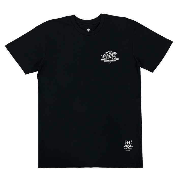 The Bay Tee by DOC from Other is a black short-sleeve classic fit t-shirt featuring a small white “The Bay” graphic on the left chest and a subtle white logo near the bottom right hem. Part of The Bay Collection, it is shown laid flat against a plain white background.