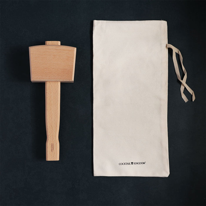 Wooden muddler and cloth pouch on a black background