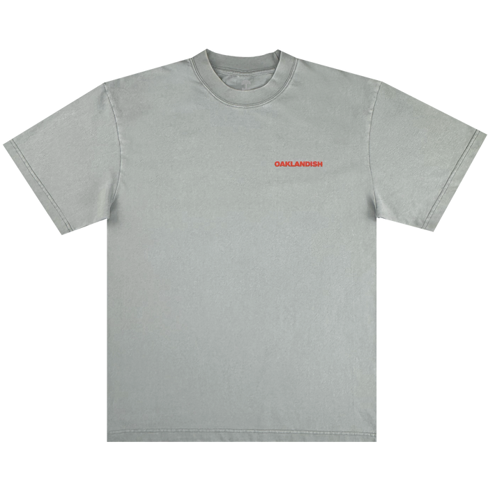 The Oaklandish Tiger Blood Tee is a vintage grey, heavy-weight cotton shirt with "OAKLANDISH" in small bold red uppercase letters on the left chest, ribbed crew neckline, and no other graphics or designs.