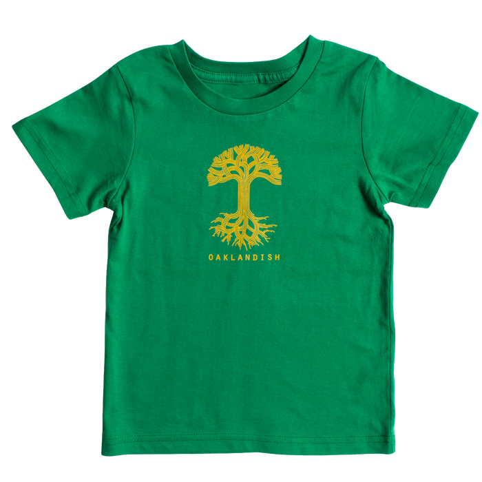 The Toddler Oaklandish Classic Logo Tee by Oaklandish is a Kelly green 100% cotton T-shirt featuring a large yellow tree with visible roots centered on the chest. Below the tree, "OAKLANDISH" is written in uppercase yellow letters. The T-shirt is displayed on a plain white background.