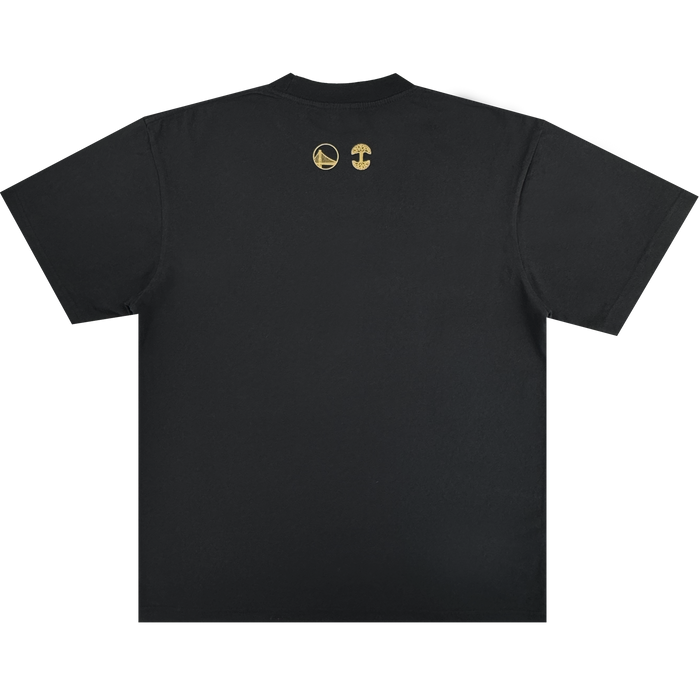 The Town Doodle Tee by Other is a black short-sleeve t-shirt shown from the back, featuring two small gold logos below the collar: one is a basketball with a bridge, representing the Golden State Warriors, and the other is a mushroom design from the Warriors x Oaklandish Town Collection. The rest of the shirt remains plain and unadorned.