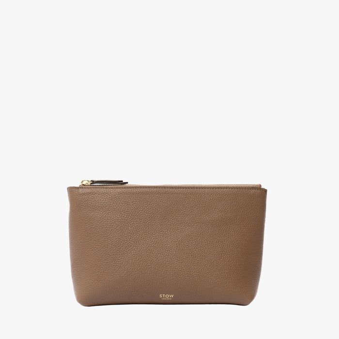 STOW London's travel pouch in Mocha pebbled leather on a light grey background featuring a YKK zip and a fine gold embossed logo on the front