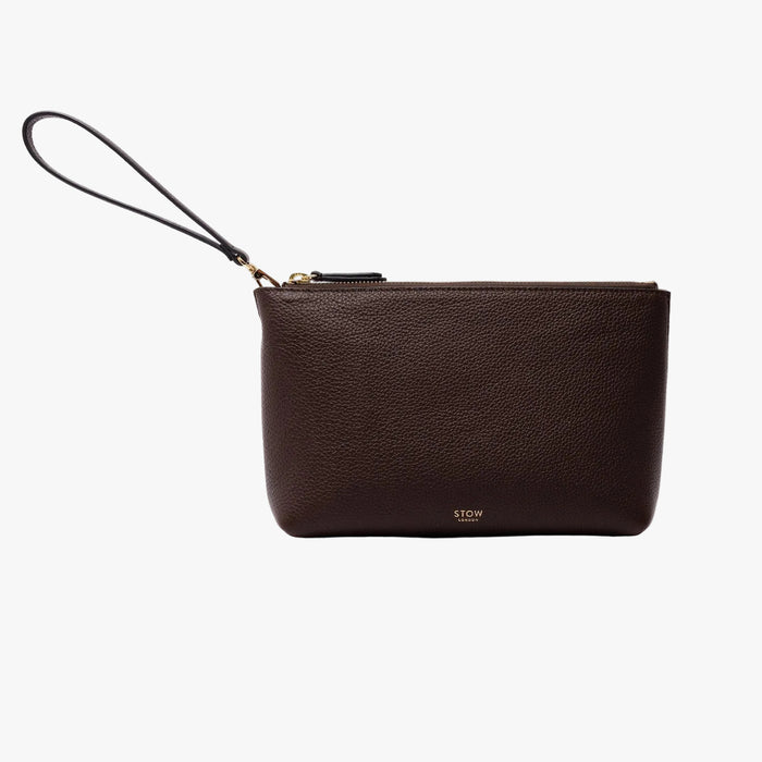 STOW London's travel pouch in Navy pebbled leather on a light grey background featuring its detachable wrist strap, a YKK zip and a fine gold embossed logo on the front bottom