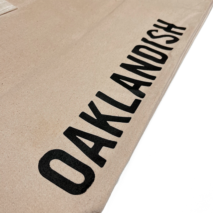 Close up of Oaklandish wordmark on brown natural denim extra large tote bag.