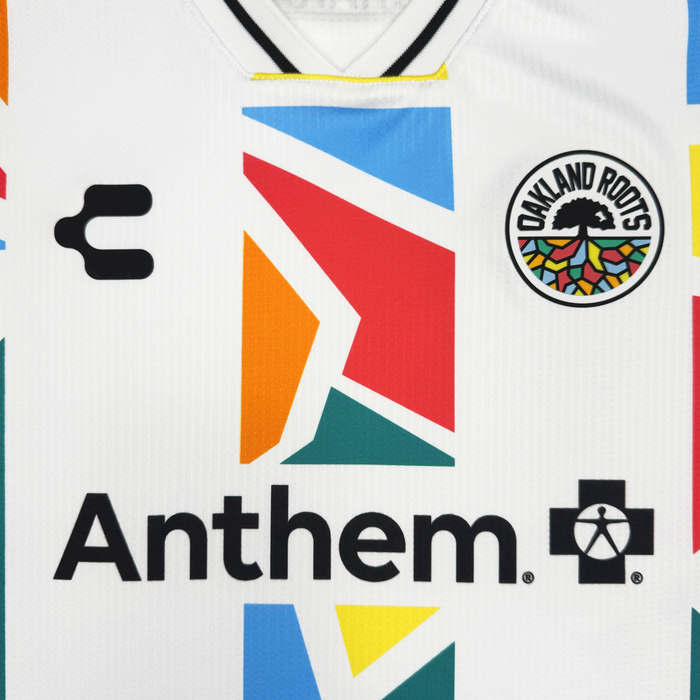 Close-up of the Unisex Mosaic in Motion Kit by Oakland Roots SC: this 2026 jersey features vibrant geometric patterns, the signature tree and rainbow logo, a bold "Anthem" sponsor, and a striking black "C" by CHARLY.