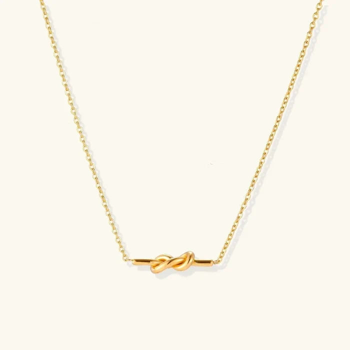 Unity Knot Necklace in polished gold-tone metal, featuring a fine cable chain and a small horizontal pendant with interwoven loops.