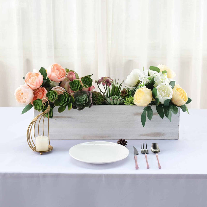 Floral centerpiece arrangement with peonies and succulents on a dining table.