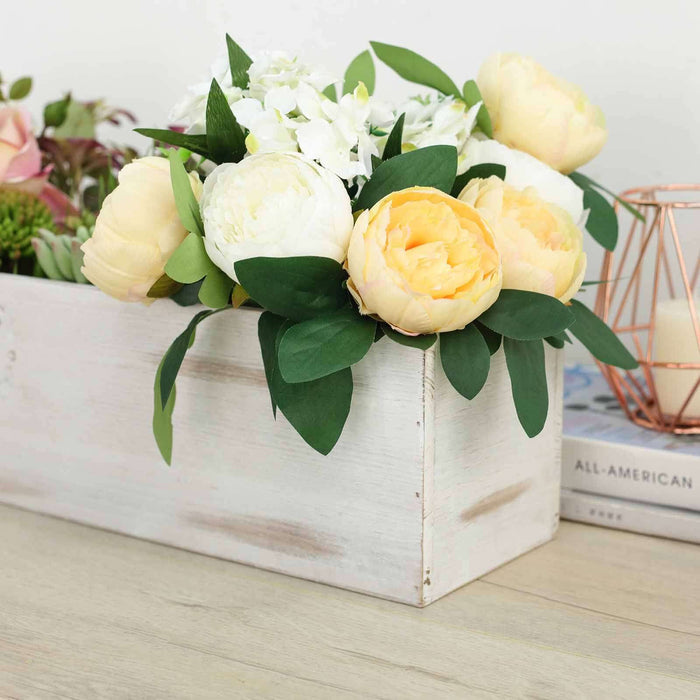 Floral arrangement in a wooden box with peonies and greenery.