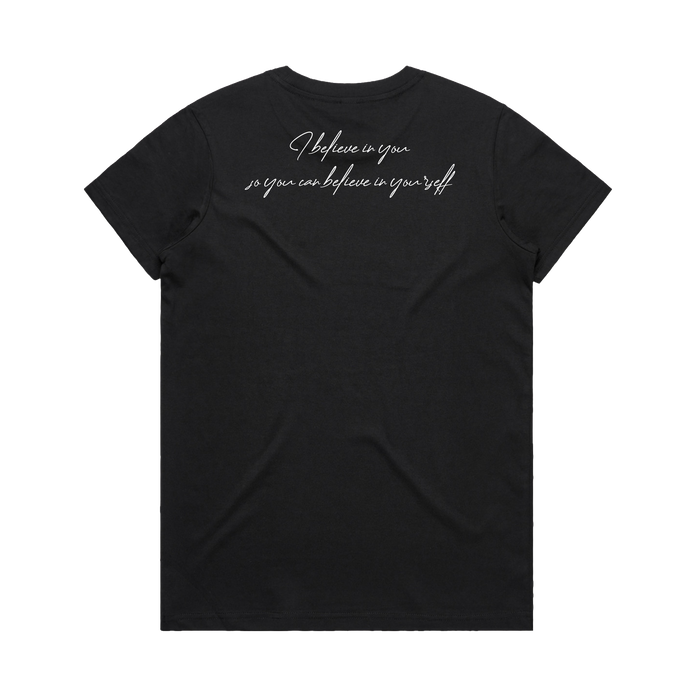 The Women's Coach Beam's Legacy Tee by Oaklandish is a black short-sleeve t-shirt laid flat, back facing up, featuring white cursive text near the upper back: "I believe in you, so you can believe in yourself." Inspired by Coach John Beam.