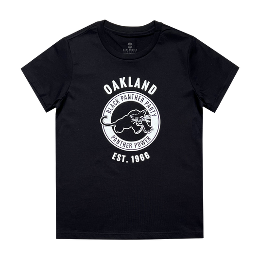 A black Women's Black Panther Power Tee from Oaklandish featuring a circular emblem with a panther illustration in the center. White text above and around the emblem reads "OAKLAND BLACK PANTHER PARTY PANTHER POWER," and additional text below reads "EST. 1966." Celebrating community organizations, the brand label "GALLANTHAWK" is inside the neckline.