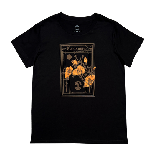 The Women's Blossom Tee by Oaklandish is a black t-shirt featuring a graphic design of California's state flower, orange poppies, centered on the front. The design is embellished with gothic-style borders and symbols surrounding the flowers, with "Oshkosh" elegantly written at the top. Available in women's sizes.