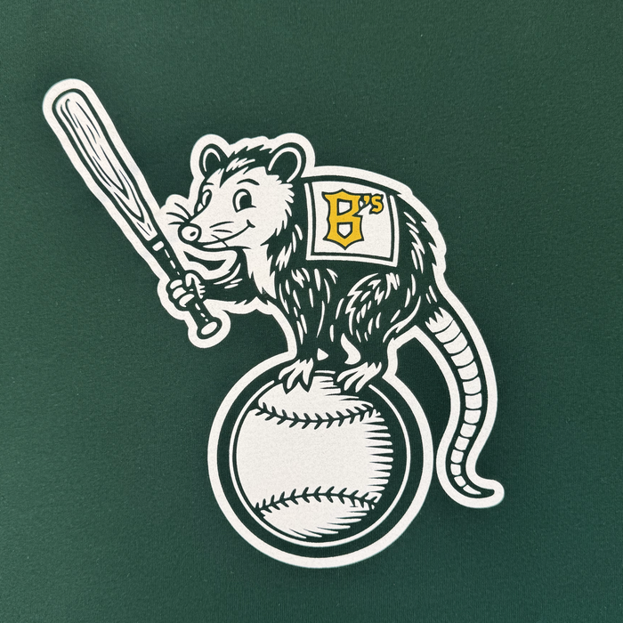 Cartoon opossum with a baseball bat stands on a baseball, wearing an Oakland Ballers jersey with a green "B's," set on solid green—featured on the Women's Clutch Tee by Oakland Ballers for the new Pioneer League team.