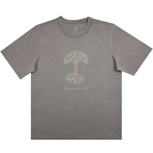 The Women's Oaklandish Classic Logo Heavy Tee by Oaklandish features an oversized fit in faded grey, showcasing a striking light beige tree design with intricate branches and roots. Crafted from heavy-weight 100% cotton, it includes "OAKLANDISH" text beneath the tree, a crew neck, and short sleeves for comfort.