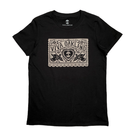 The Women's Viva Oakland Tee by Oaklandish is a black T-shirt made from 100% cotton, featuring a bold beige rectangular graphic with the words "Viva Oakland." Below the graphic, a heart rests amid artistic leaf and flower designs. This classic fit tee comes with the "Oaklandish" logo printed on the inside neckline.