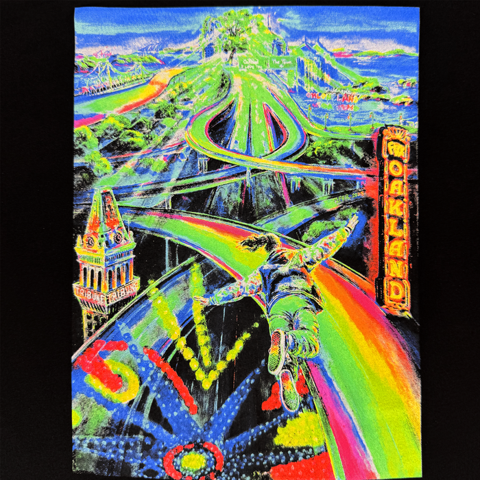 A vibrant figure in colorful attire soars along a twisting rainbow road above a neon-lit cityscape proudly labeled “OAKLAND,” with landmarks, winding streets, and fireworks illuminating the scene. Radiant blues, greens, yellows, reds, and oranges combine for a surreal, dreamlike effect reminiscent of classic Oakland art—making this the perfect inspiration for the Other brand Women’s Yay Area Tee.