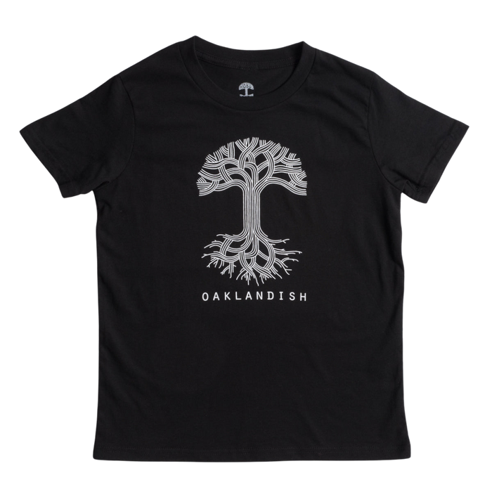 The image shows the Youth Oaklandish Classic Logo Tee by Oaklandish, a black tee made from 100% cotton. It features a white graphic of a tree with branches extending upward and roots spreading downward. Below the tree graphic, "OAKLANDISH" is written in white capital letters. The kids' t-shirt is laid flat against a white background.