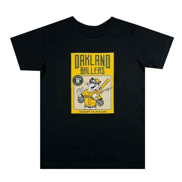 The Oakland Ballers Youth Scrappy Rookie Tee is a black shirt with a yellow graphic of mascot Scrappy the Rally Possum in a baseball uniform holding a bat, plus “Oakland Ballers,” “Scrappy T.R. Possum,” logo, and autograph.