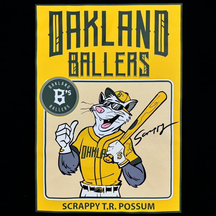 The Youth Scrappy Rookie Tee by Oakland Ballers showcases mascot Scrappy the Rally Possum in uniform, cap, and with his bat, giving a thumbs-up on a yellow background with "OAKLAND BALLERS" above and "SCRAPPY T.R. POSSUM" below.